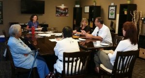 Photo of Kathleen Kenney speaking to the group gathered around a conference table