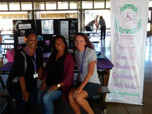 Photo of Julie, Lani, and Kathleen sitting at AILH display table