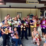 Group photo of police officers, AILH staff and volunteers holding stuffed animals