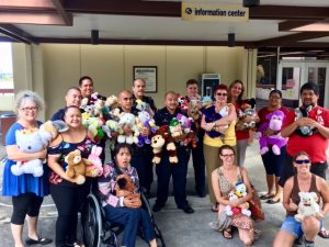 Group photo of police officers, AILH staff and volunteers holding stuffed animals