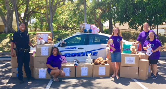 Photo of staff next to police car with boxes of stuffed animals