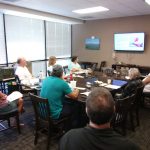 Photo of Maui support group seated around conference table looking at screen